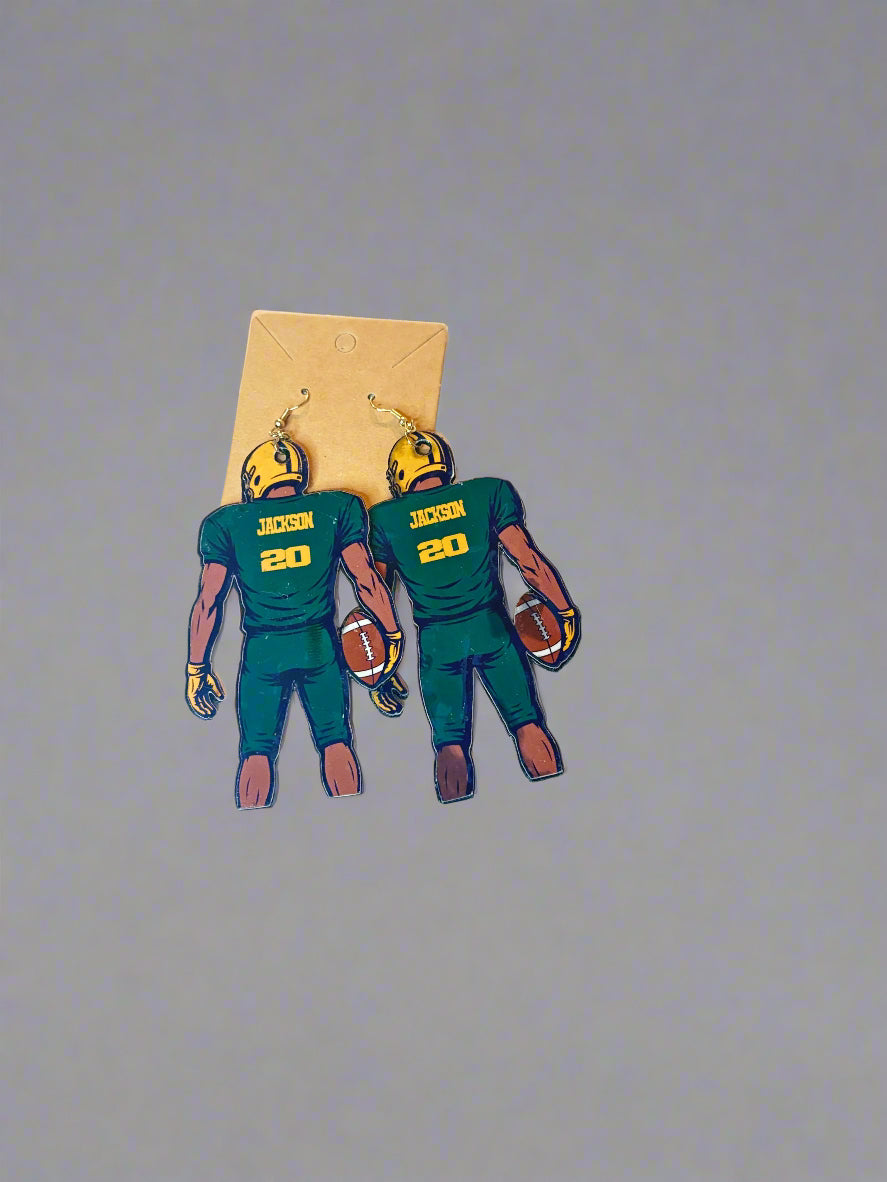 Pair of football player earrings on a white surface with a grid background