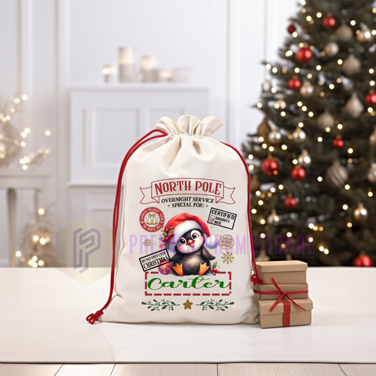 Personalized Christmas gift bag with penguin design in front of a decorated Christmas tree.